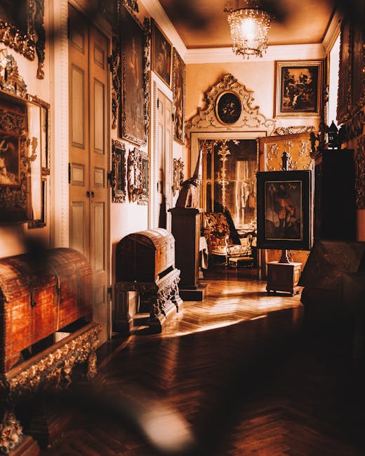 A luxurious, ornately decorated interior room with classic furniture and numerous framed paintings and mirrors on the walls. The space features a polished wooden floor, a decorative ceiling with a cha